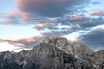 rugged mountain range under warm sunset light, with thick, moody clouds across the peaks. minimalist mountain background with empty space