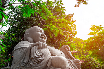 Serene stone buddha statue in lush greenery with sunlight