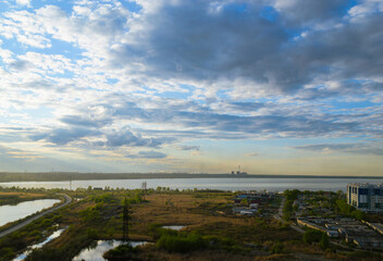 Fototapeta premium Picturesque scenery with a field and a lake under clouds at sunset