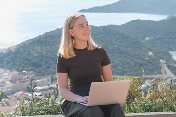 Remote Work,digital nomad enjoys remote work with a laptop in a scenic mountain setting.freedom of location-independent work, online business, and the balance of work and travel.