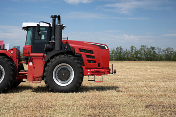 Close-up a red tractor work with a plow in a field. Start tillage after harvest.