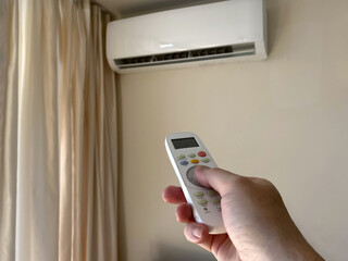 Close-up a man's hand turns on an air conditioner using a remote control in an apartment or house.