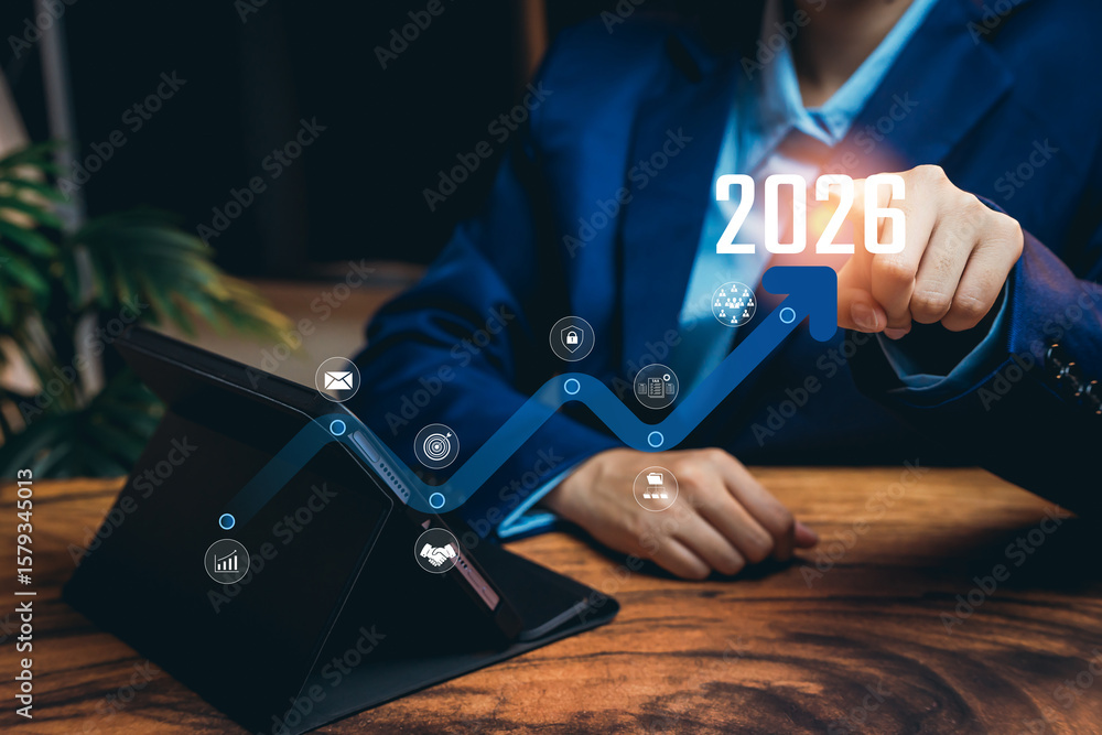 Poster business professional pointing at future growth projection for 2026 with digital interface and table