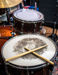 Closeup of a drum set featuring wooden drumsticks resting on a snare drum. Focus on music, rhythm, performance. Ideal for musicrelated content, ads, and backgrounds.
