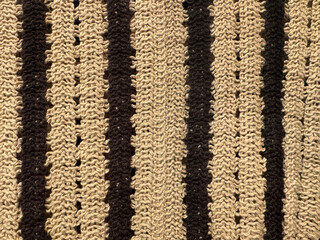 Close up of knitted fabric texture in vertical stripes pattern. In beige and black stripes color....