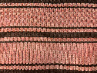 Close up of knitted fabric texture in horizontal linear stripes pattern. In pink, maroon, and black...