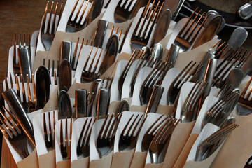 Image of forks, knives, and spoons neatly wrapped in paper napkins, organized in a standing...