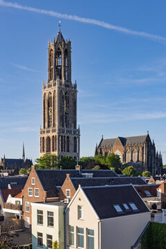 The iconic Dom Tower of Utrecht, Netherlands, rising above the city's rooftops on a clear summer day, a symbol of Dutch history.