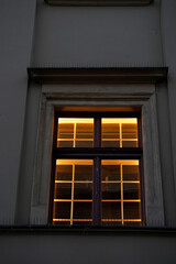 Obraz premium Warm glowing window lights. Evening city building. Architectural detail night. Cozy urban ambiance.
