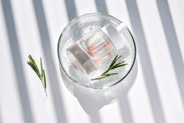 A clear bottle of serum in a petri dish. A sample of the texture of the product.