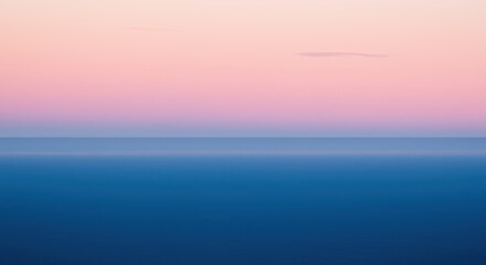 Obraz premium Serene view of a tranquil blue sea beneath a pastel pink and purple gradient sky at dusk