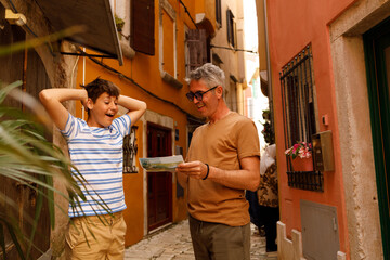 A father and son on a sightseeing trip in Rovinj, Croatia. . They are holding a map. Both appear...