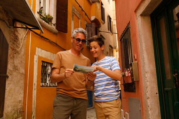 A father and son on a sightseeing trip in Rovinj, Croatia. . They are holding a map. Both appear...
