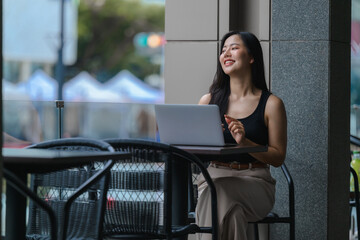 Young Asian Freelancer Working on Laptop in Outdoor Cafe
