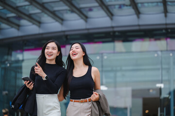 Two young businesswomen walking and laughing in the city