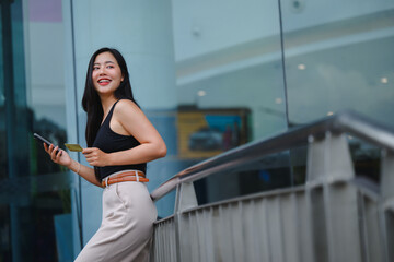 Young business woman holding credit card and using smartphone for online shopping