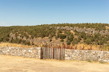Fototapeta premium a stone wall with a double wooden gate in the center and a mountainous landscape in the background