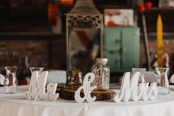 Rustic wedding reception table with Mr and Mrs white wooden signs, glass jars, wood slice...