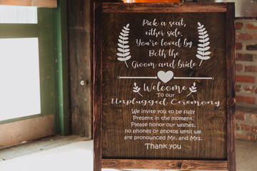 Rustic wooden wedding sign with white lettering explaining unplugged ceremony rules, welcome...