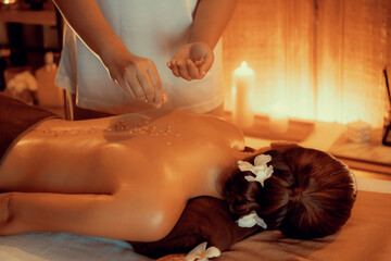Woman customer having exfoliation treatment in luxury spa salon with warmth candle light ambient....