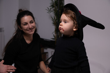 Baby girl wearing witch costume for halloween with smiling mother