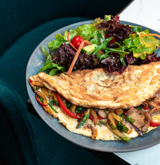 Stuffed Vegetable Omelette with Mixed Leaf Salad. Bright cherry tomatoes and colorful peppers. Perfect for healthy menus, breakfast, cooking blogs.