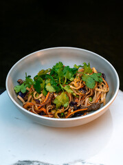 Asian beef udon noodles with bell pepper, red cabbage, scallions, sesame and fresh cilantro in...