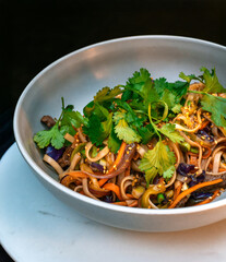 Asian beef udon noodles with bell pepper, red cabbage, scallions, sesame and fresh cilantro in...
