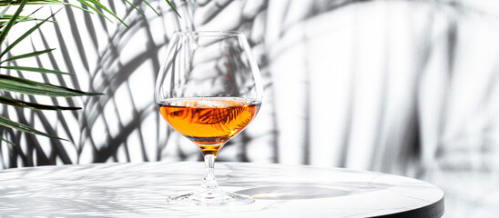 glass of French cognac on a modern table, showcasing its amber hue against a backdrop of intricate...