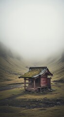 Small cabin in foggy mountain field with muted colors and peaceful mood.