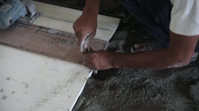 a flooring installer or floor technician installing the C clamp on the marble slab and guide before starting the cutting work. the slab is laid on a layer of fine sand to avoid cracks during cutting.