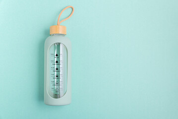 A glass water bottle with time markers on a blue background.