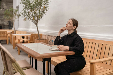 Woman Coffee Cafe: Pensive woman drinks coffee alone at outdoor cafe for relaxation, daytime.