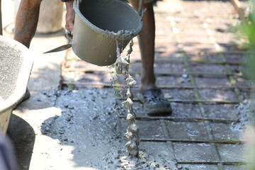 Cement pouring on steel rebar grid during construction, cement pouring close-up with wet texture in daylight, cement pouring on reinforced foundation floor