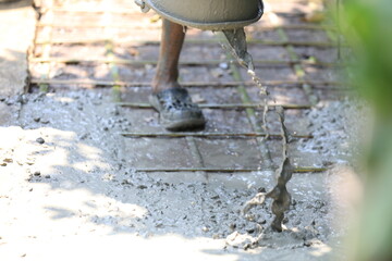 Cement pouring on steel rebar grid during construction, cement pouring close-up with wet texture in daylight, cement pouring on reinforced foundation floor