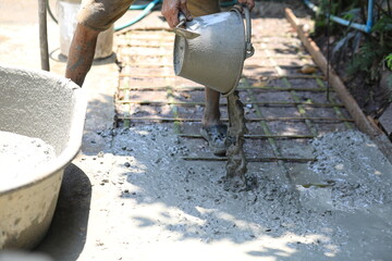 Cement pouring on steel rebar grid during construction, cement pouring close-up with wet texture in daylight, cement pouring on reinforced foundation floor