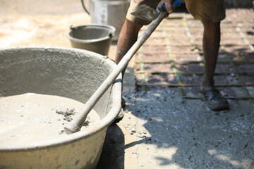 Cement pouring on steel rebar grid during construction, cement pouring close-up with wet texture in daylight, cement pouring on reinforced foundation floor