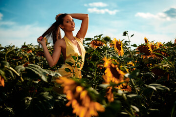 Fashion model posing in sunflower field on sunny day