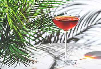 vibrant red cocktail with whiskey, port wine, amaro, and bitters rests elegantly on a marble table,...