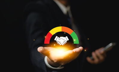 Businessman holding glowing handshake icon with customer satisfaction meter. Concept of...