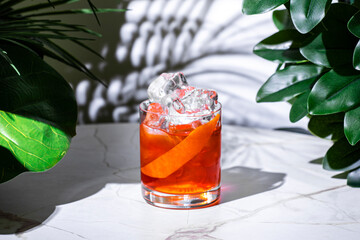 Negroni cocktail in a glass with ice and orange twist on marble table