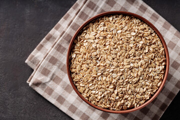 Rolled Oats in Ceramic Bowl on Brown Checkered Napkin Top View