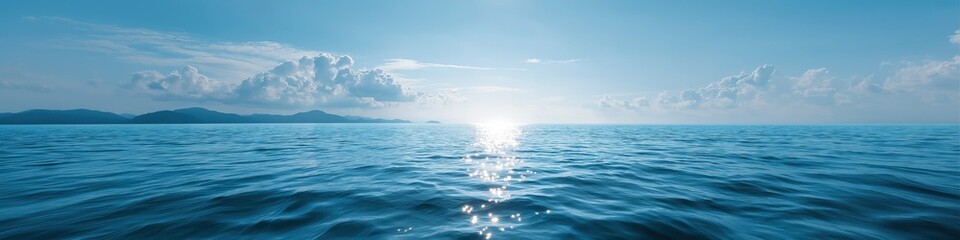 Fototapeta premium Tranquil ocean panorama at sunrise with sparkling waves and distant mountains