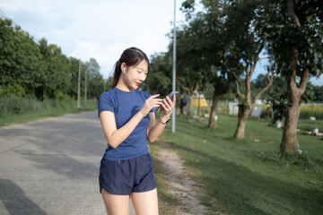 A woman is walking down a road while looking at her cell phone