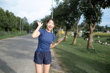 A woman is standing on a road, smiling and holding a cell phone