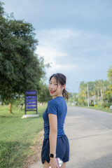 A woman is walking down a road with a blue shirt and shorts