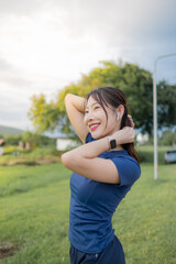 A woman is standing in a park, wearing a blue shirt and red lipstick
