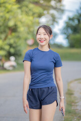 A woman is walking down a street wearing a blue shirt and blue shorts