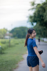 A woman is walking down a path with a cell phone in her hand