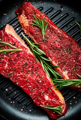 Raw beef sirloin steaks on grill pan, ready for cooking. Black background, top view